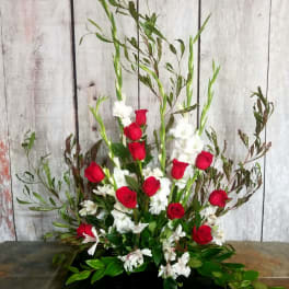 Tall floral arrangement with red roses and white flowers in a low black container