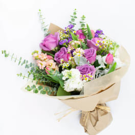 Bouquet of purple roses and mixed small flowers wrapped in kraft paper