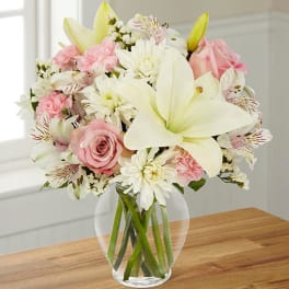 Pink and white bouquet with lilies and roses in a clear glass vase