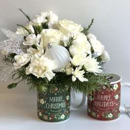 White floral arrangement in a Christmas mug with a silver ornament