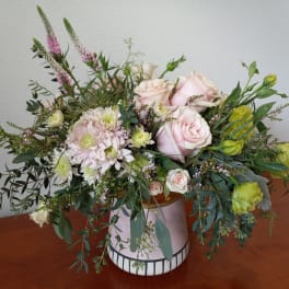 Pink roses and pale blooms arranged in a ceramic vase