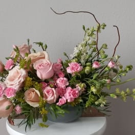 Pink and peach roses with small pink blooms in a low gray bowl