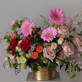 Mixed pink and peach flowers in a gold vase