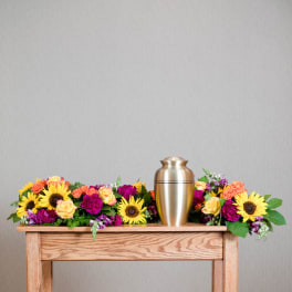 Colorful floral arrangement with a gold urn centerpiece on a wooden table