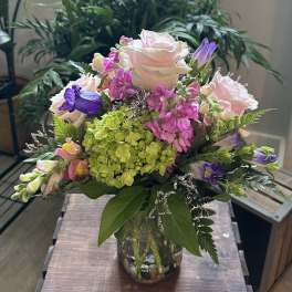 Mixed pink and purple flowers in a glass vase