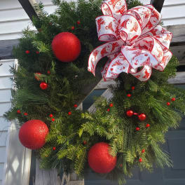 Christmas wreath with red ornaments and a white ribbon bow