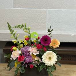 Mixed flower arrangement in a dark rectangular container