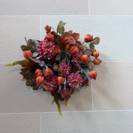 Wall-mounted floral arrangement with pink blooms and orange buds