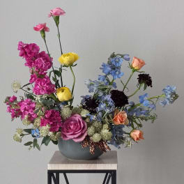 Mixed bouquet in a gray vase with pink, yellow, blue, and peach flowers