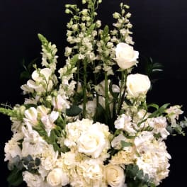 White floral arrangement with roses, hydrangeas, and tall snapdragons