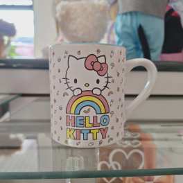Hello Kitty mug with a rainbow graphic on a glass shelf