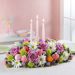 Floral centerpiece with pink roses and white daisies around three candles