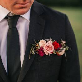 Boutonniere with pink roses and red flowers on a suit jacket