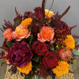 Mixed bouquet of red and orange roses with marigolds in a woven basket