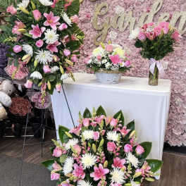 Pink and white floral arrangements with lilies and roses at a decorated display