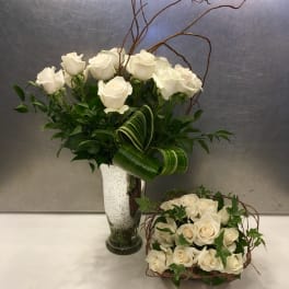 White rose arrangements in a vase and basket with curly branches