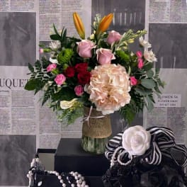 Mixed bouquet in a glass vase with pink roses, lilies, and hydrangea