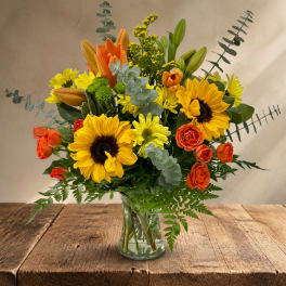 Bouquet of yellow sunflowers and orange roses in a clear glass vase
