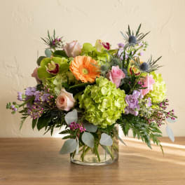Mixed bouquet with roses, hydrangeas, and an orange gerbera daisy in a glass vase