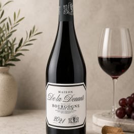 Bottle of red wine beside a glass of wine and grapes
