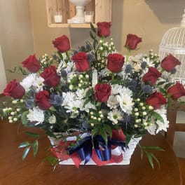 Basket arrangement of red roses and white daisies with a ribbon bow