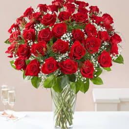 Bouquet of red roses with baby's breath in a clear glass vase