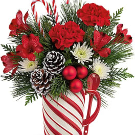 Holiday bouquet in a candy cane mug with red flowers and pinecones