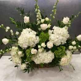 White floral arrangement with roses and hydrangeas in a basket