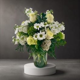 White and pale yellow floral arrangement in a glass vase