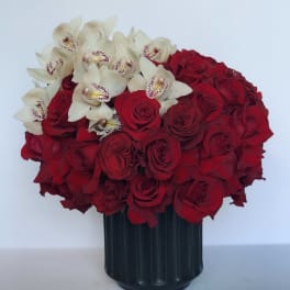 Red roses and white orchids arranged in a black vase