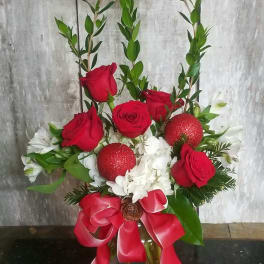 Red roses and white flowers in a glass vase with a red ribbon