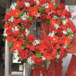 Large red floral wreath on a stand with hanging rose garlands