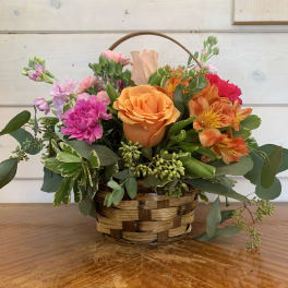 Basket arrangement with orange roses and pink flowers