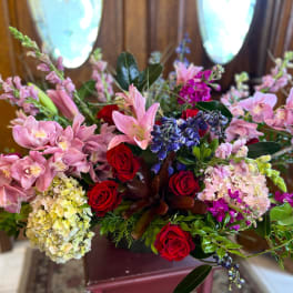 Mixed bouquet with pink orchids, red roses, and blue flowers in a vase