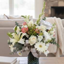 Mixed bouquet in a glass vase with white lilies, roses, and daisies