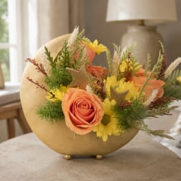 Peach roses and yellow daisies arranged in a gold crescent vase