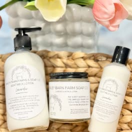 Gift set with lotion, soap, and a candle beside tulips in a woven basket