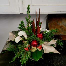 Holiday arrangement with white calla lilies, red ornaments, and ribbon