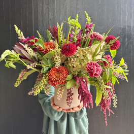 Large mixed bouquet in a beige vase with pink and orange blooms