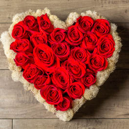 Heart-shaped arrangement of red roses with a pale filler border