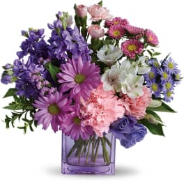 Mixed bouquet of purple, pink, and white flowers in a purple glass vase