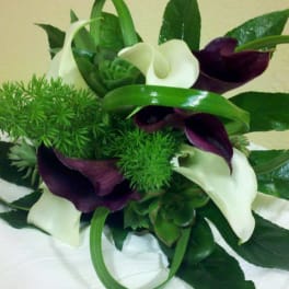 Bouquet of white and dark purple calla lilies with green foliage