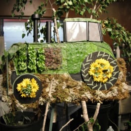 Green tractor-shaped floral display with yellow flower wheels