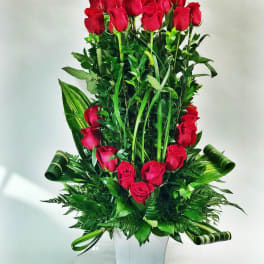 Tall arrangement of red roses in a white vase