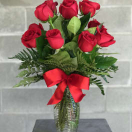 Bouquet of red roses in a glass vase with a red ribbon
