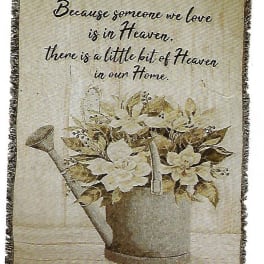 Decorative wall hanging with a watering can of white flowers and a memorial quote