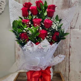Bouquet of red roses with baby's breath wrapped in white paper and a red ribbon