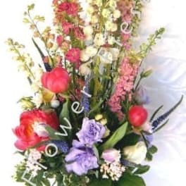 Tall mixed flower arrangement with a pink ribbon in a glass vase