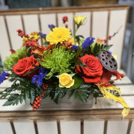 Colorful floral arrangement with red and yellow roses in a rectangular container
