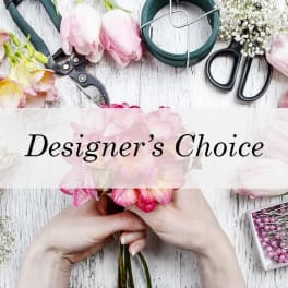 Hands holding a pink flower bouquet with floral tools and supplies nearby